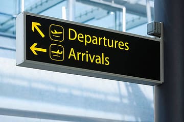 Sign pointing the way to Departures and Arrivals at an airport.